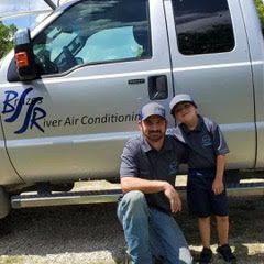 A man and a boy are posing for a picture in front of a truck.