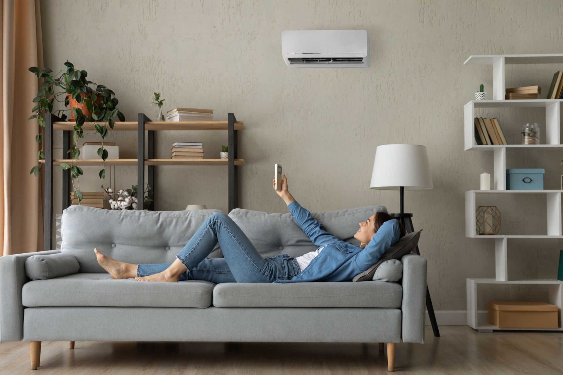 A woman is laying on a couch in a living room looking at her phone.