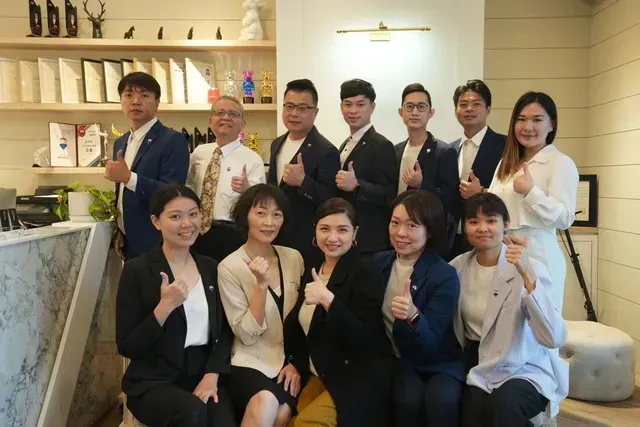 一群身著正裝的人在商務場合擺姿勢並豎起大拇指。