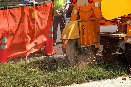 a yellow tractor is cutting a hole in the ground .