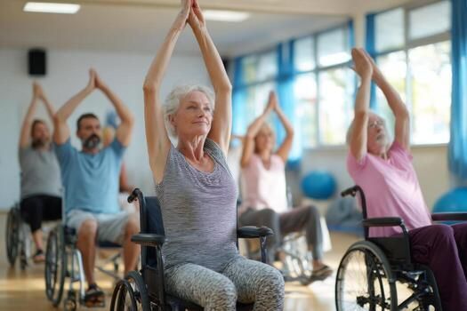 People in wheelchairs doing chair yoga with arms raised in a light-filled room.