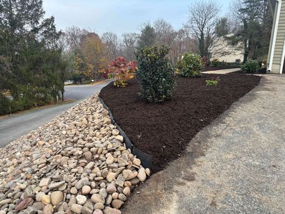 Landscaping & Cleanups Landscaped yard with rock border, dark mulch beds, shrubs, and a gravel driveway
