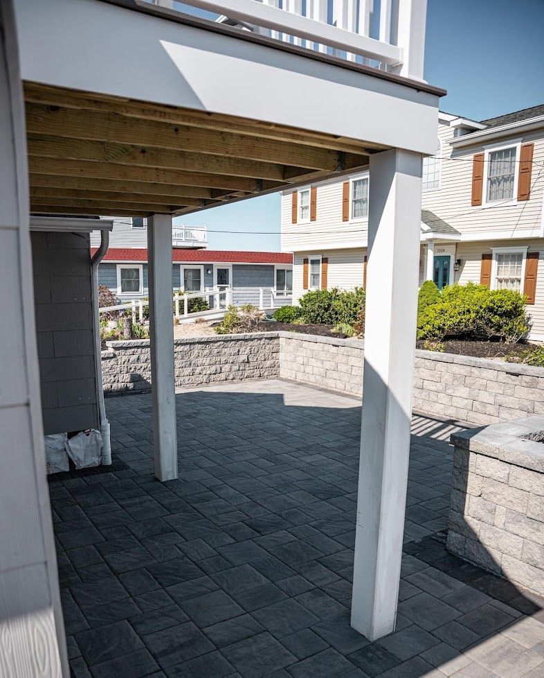 Covered patio with white columns, gray paver floor, and courtyard townhouses beyond