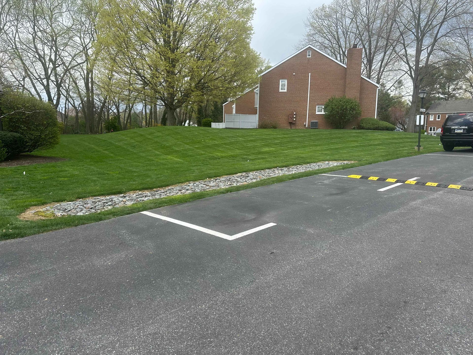 A parking lot with a brick house in the background