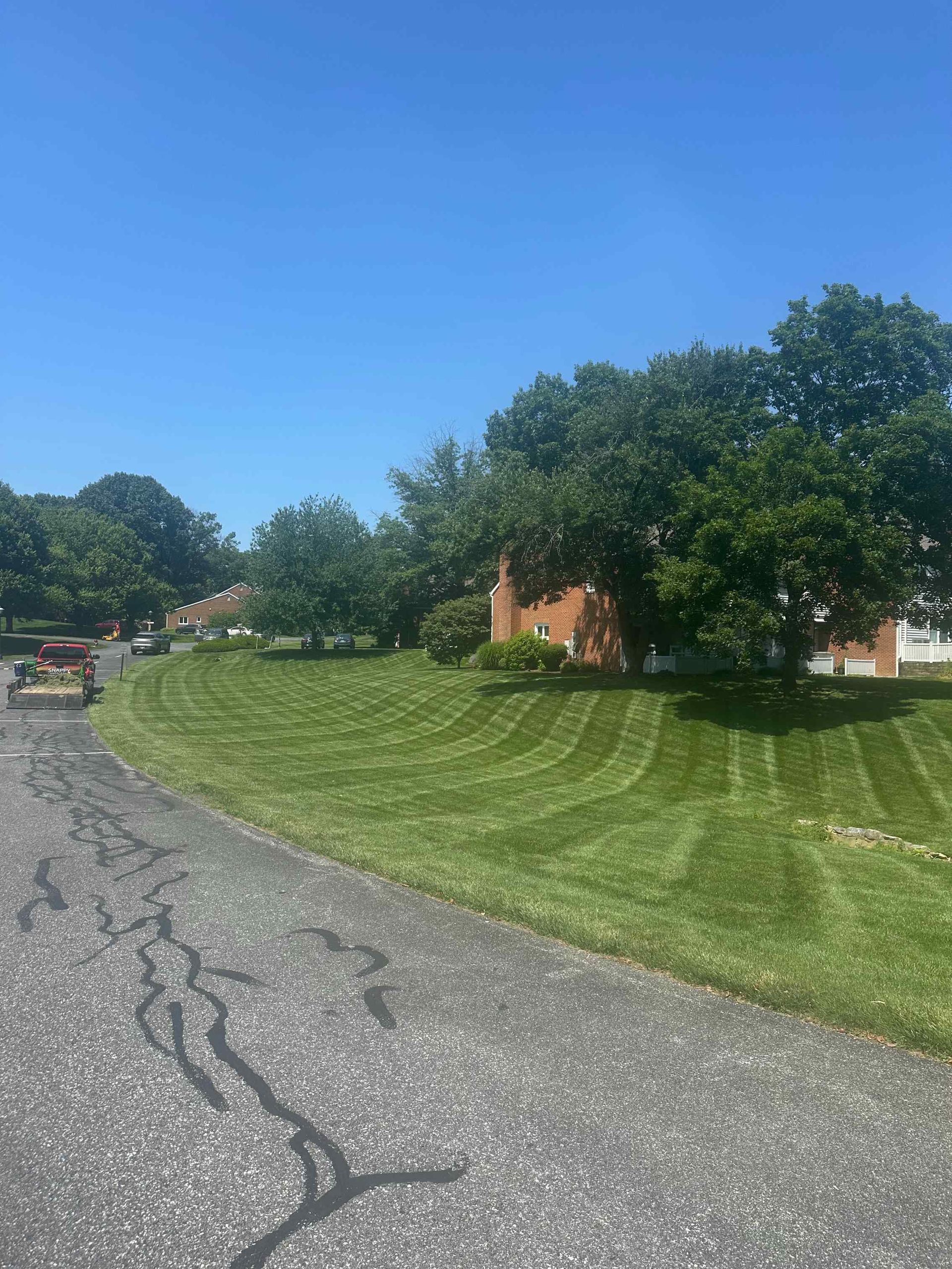 A lush green lawn is along the side of a road next to a house.