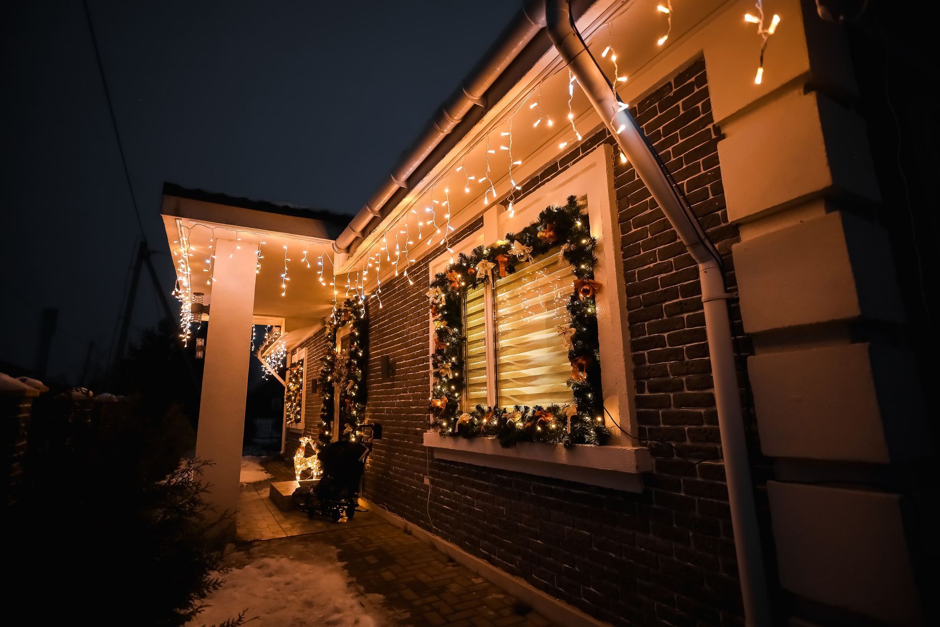 A brick house is decorated with christmas lights and a wreath.