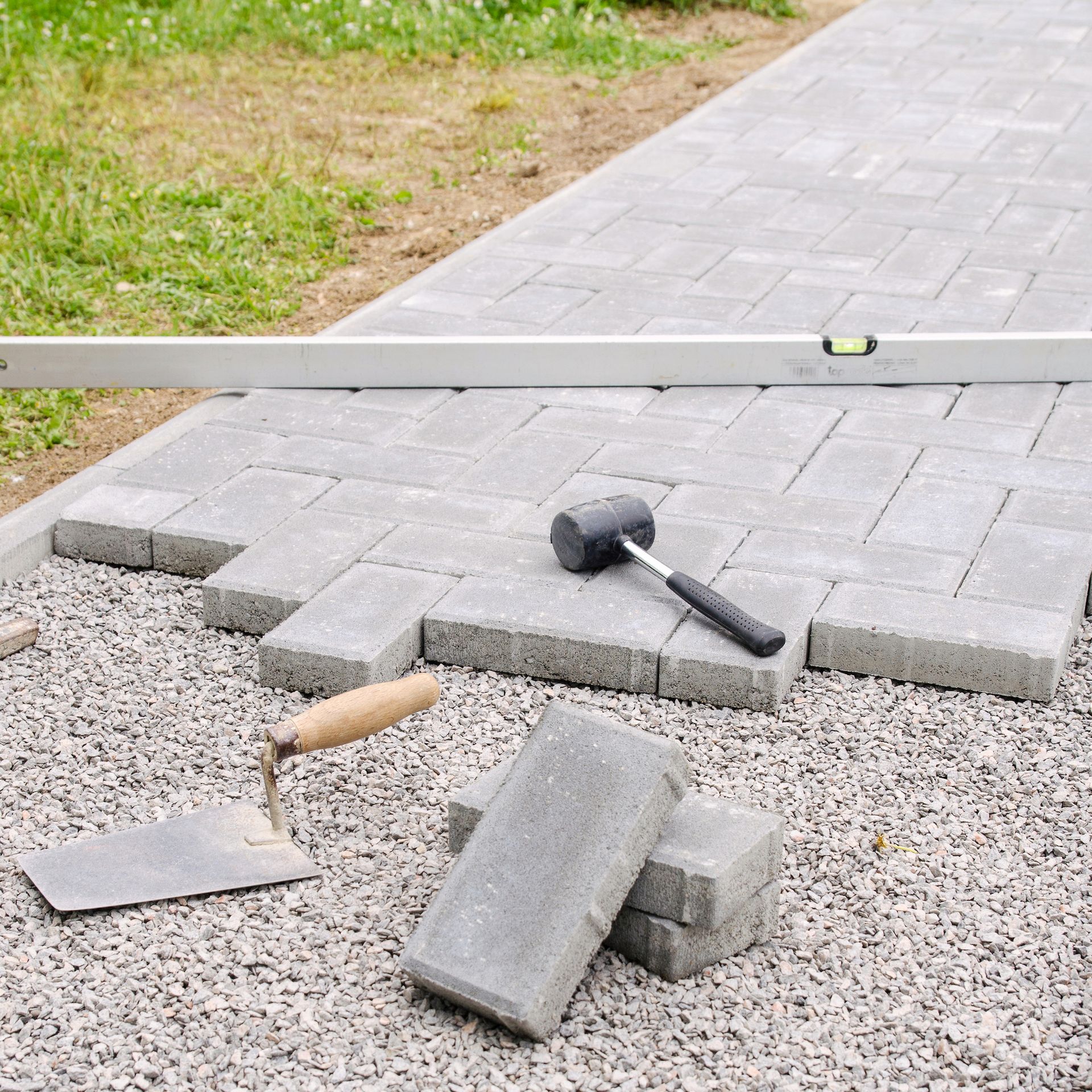 A walkway is being built with bricks and a level.