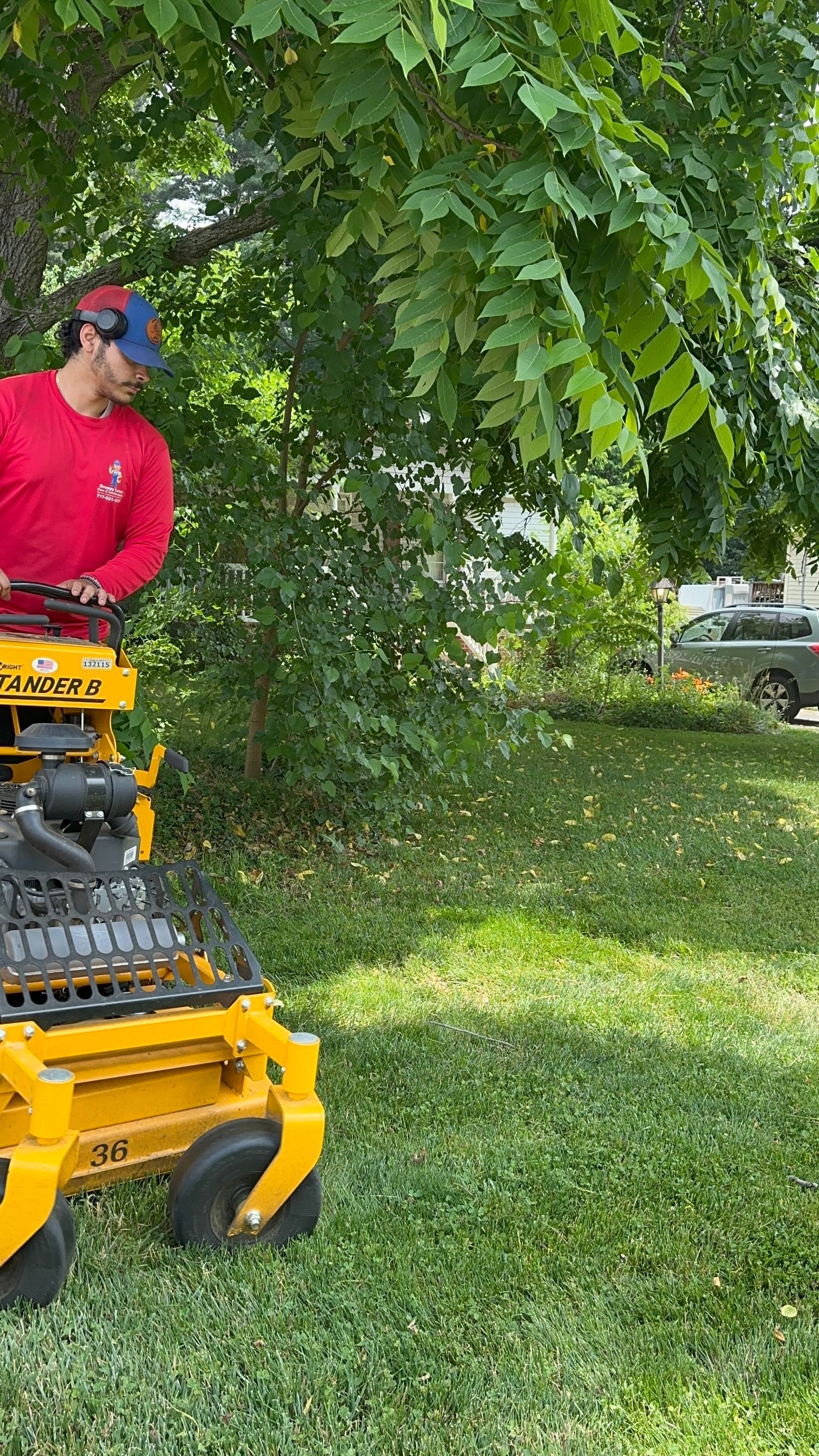 A man is riding a yellow lawn mower in a yard.