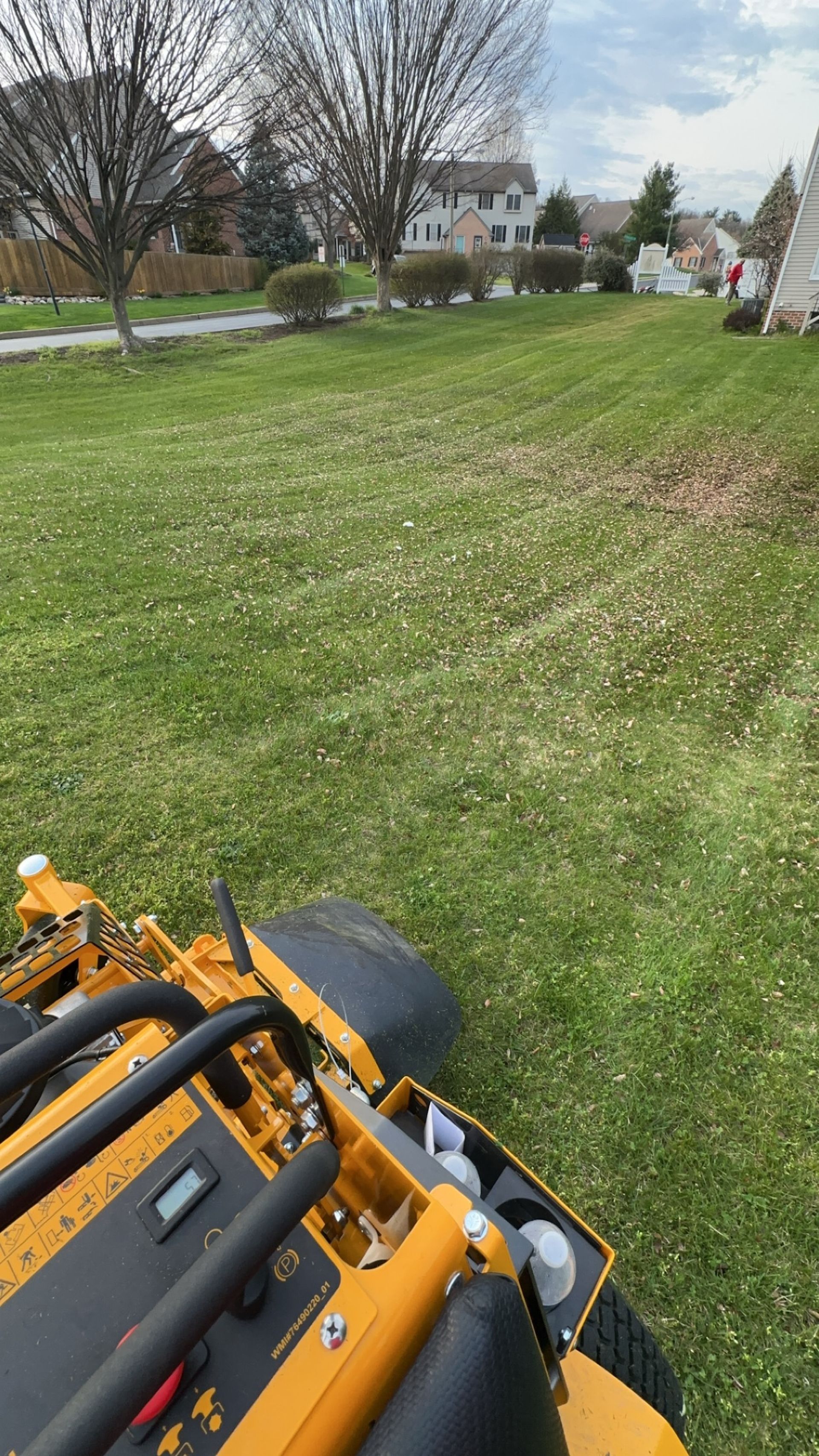 A yellow lawn mower is cutting a lush green lawn.