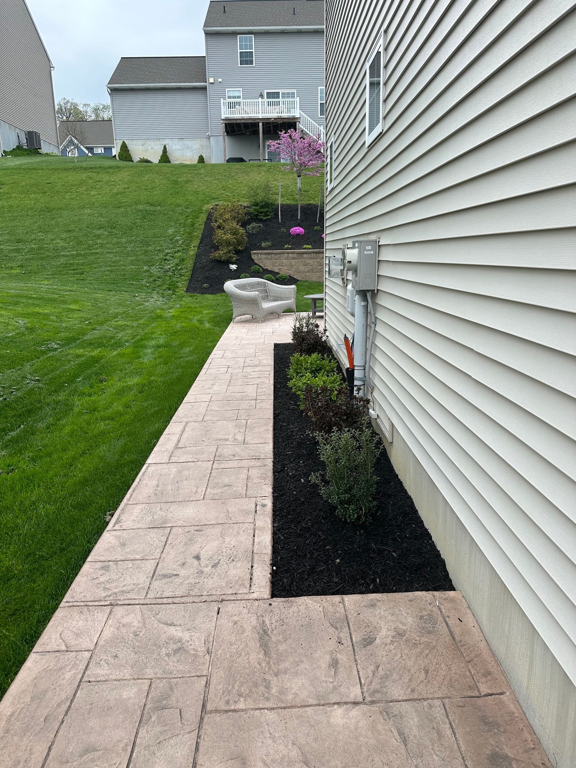 A sidewalk leading to a house with a lawn in the background.
