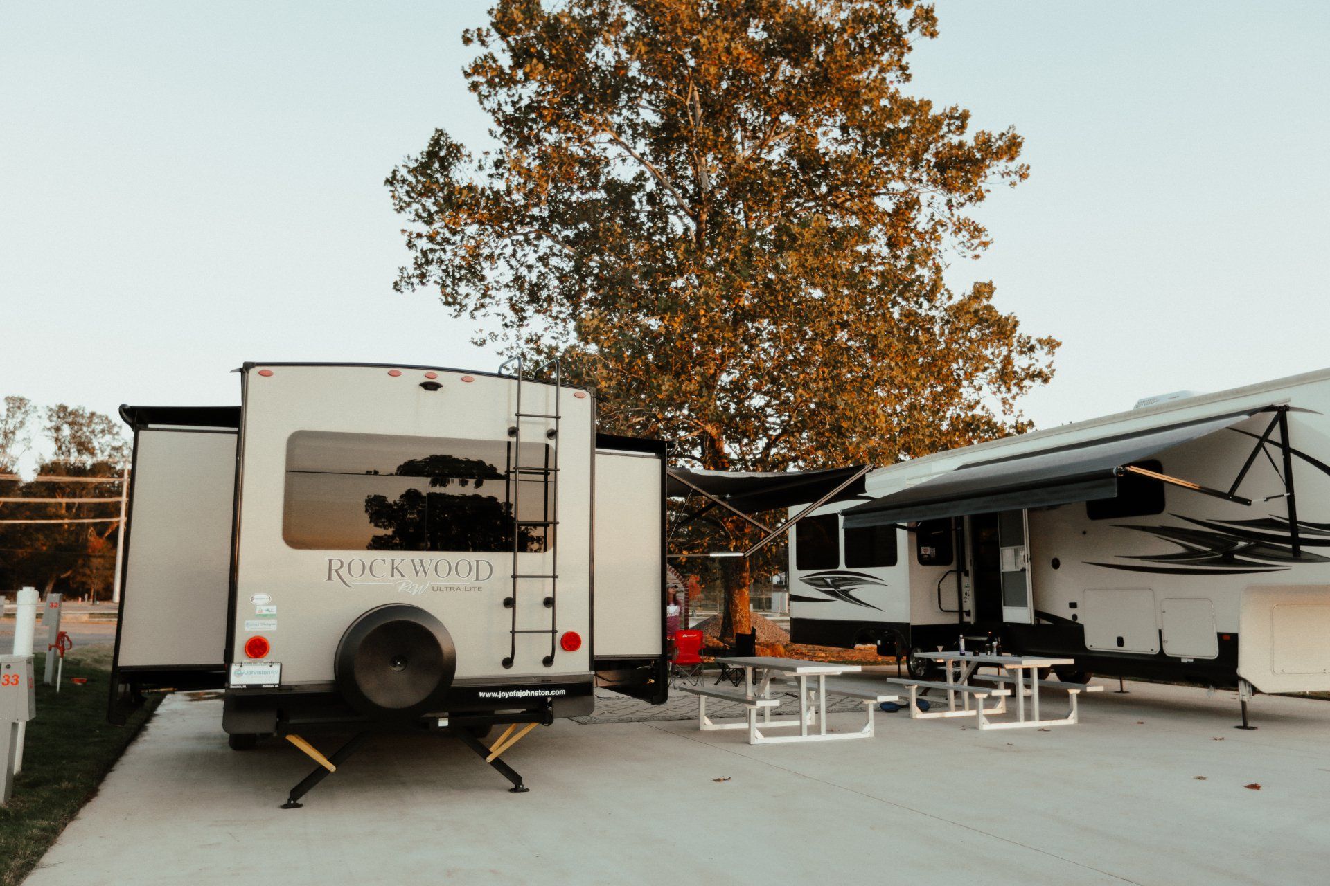 A rv is parked in a driveway next to another rv.