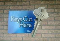 A brick wall with a sign that says keys cut here