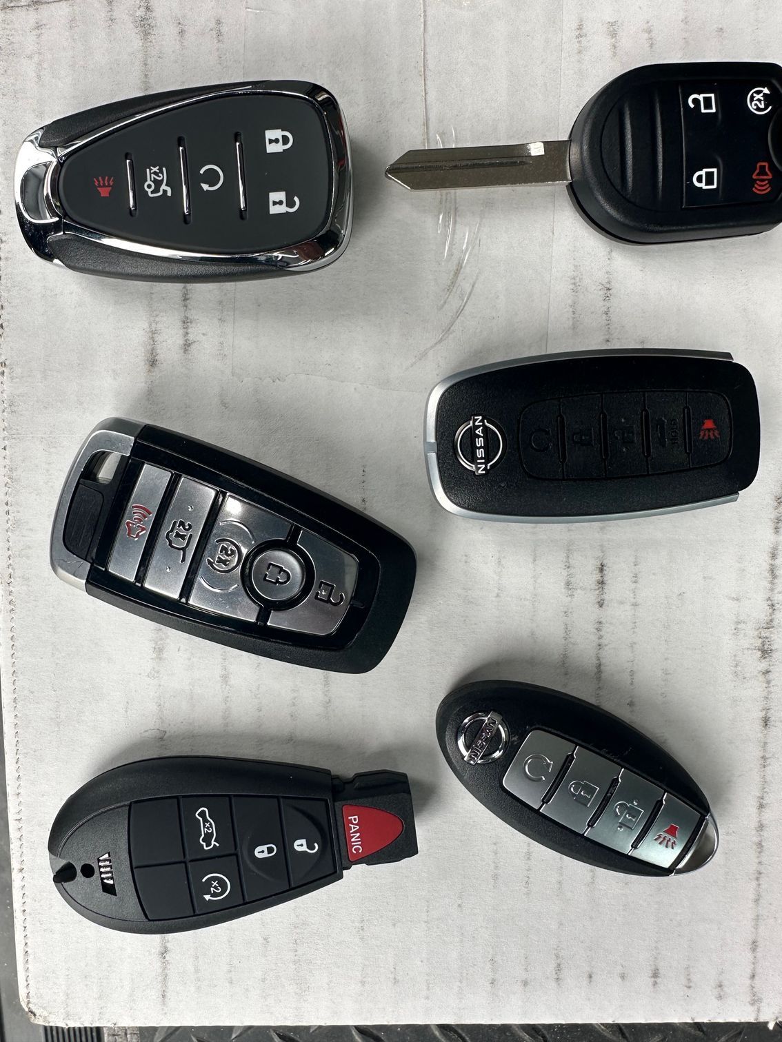 Three different types of car keys are sitting next to each other on a white surface.