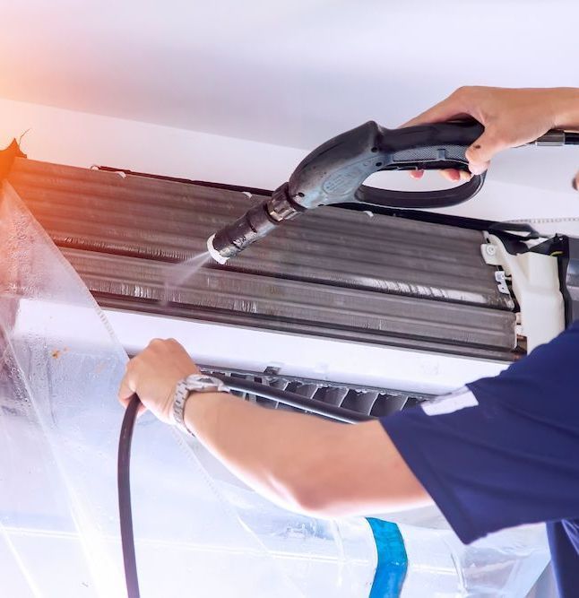 Person Cleaning an Air Conditioner With a Pressure Washer — Climacool Air Conditioning in Trinity Beach, QLD