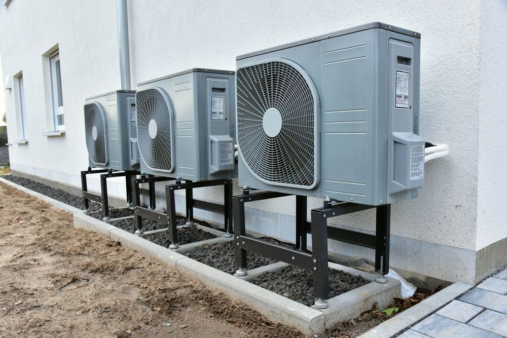 Four Gray Heat Pump Units Mounted on Black Metal Stands — Climacool Air Conditioning in Trinity Beach, QLD