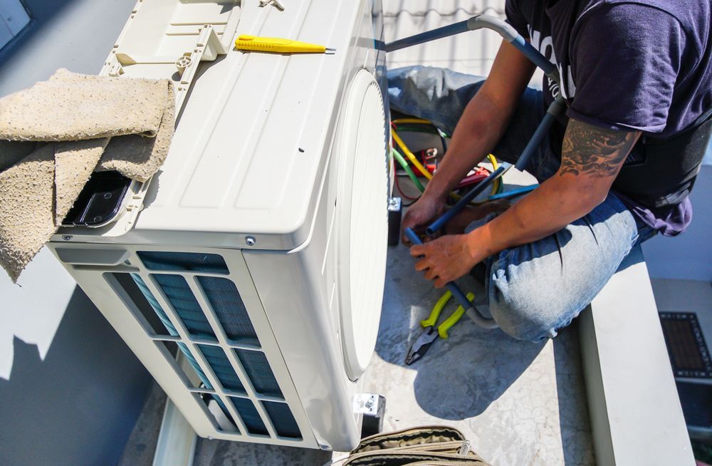 A Person Repairs an Outdoor Air Conditioning Unit — Climacool Air Conditioning in Redlynch, QLD