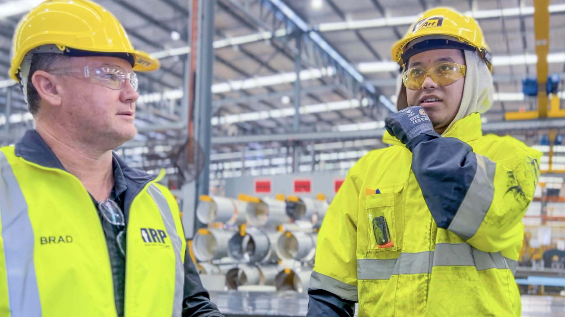 Two men in hi-vis talking in a warehouse