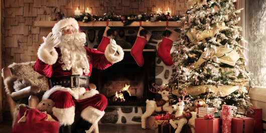 Santa Claus in his decorated grotto with a christmas tree, fire, presents and stockings