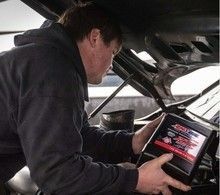 Mechanic using a tablet to diagnose a car issue under the hood.