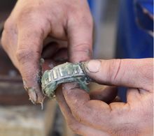 Hands holding a bearing covered in green grease.