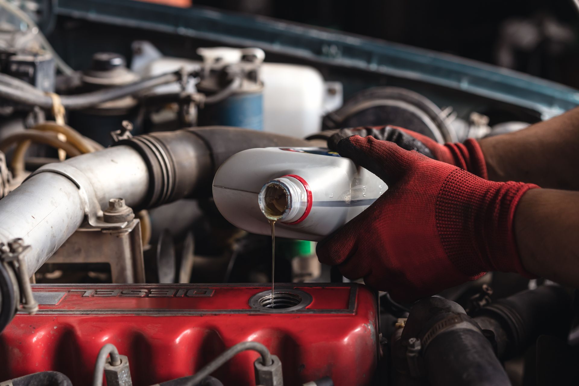 Mechanic pouring oil into a car engine, hands in red gloves. Mechanic pouring oil into a car engine, hands in red gloves.
