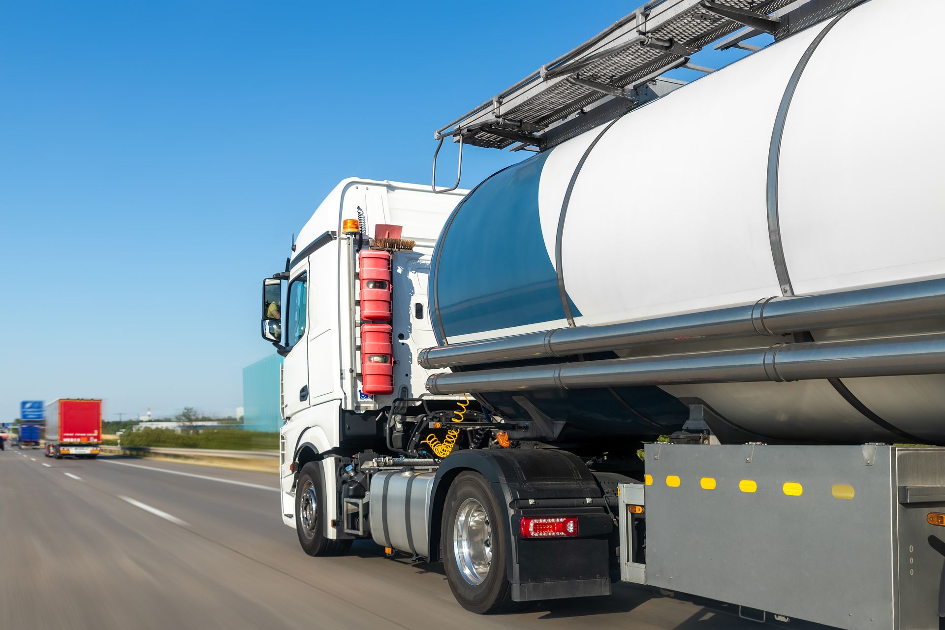White tanker truck driving on highway, blue sky. White tanker truck driving on highway, blue sky.