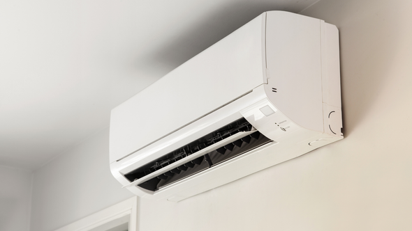 A white air conditioner is hanging from the ceiling in a room.