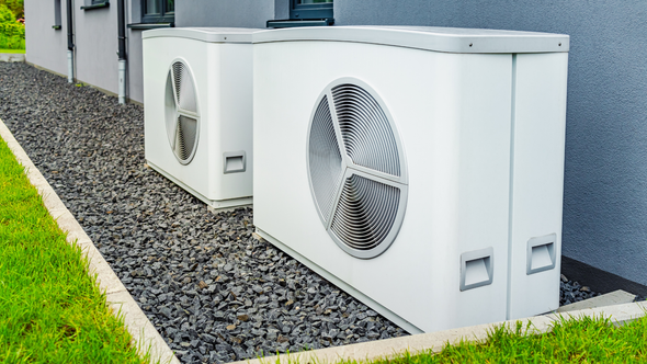 Two air conditioners are sitting next to each other on the side of a building.