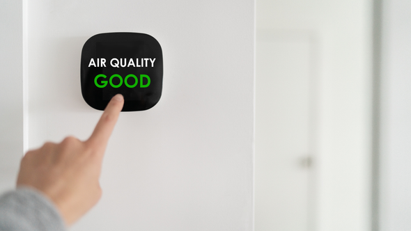 A person is pressing a button on a wall that says `` air quality good ''.