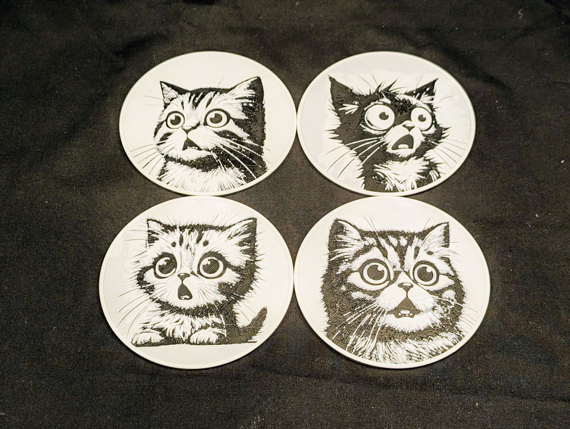 Four coasts with different cute cat faces on them.