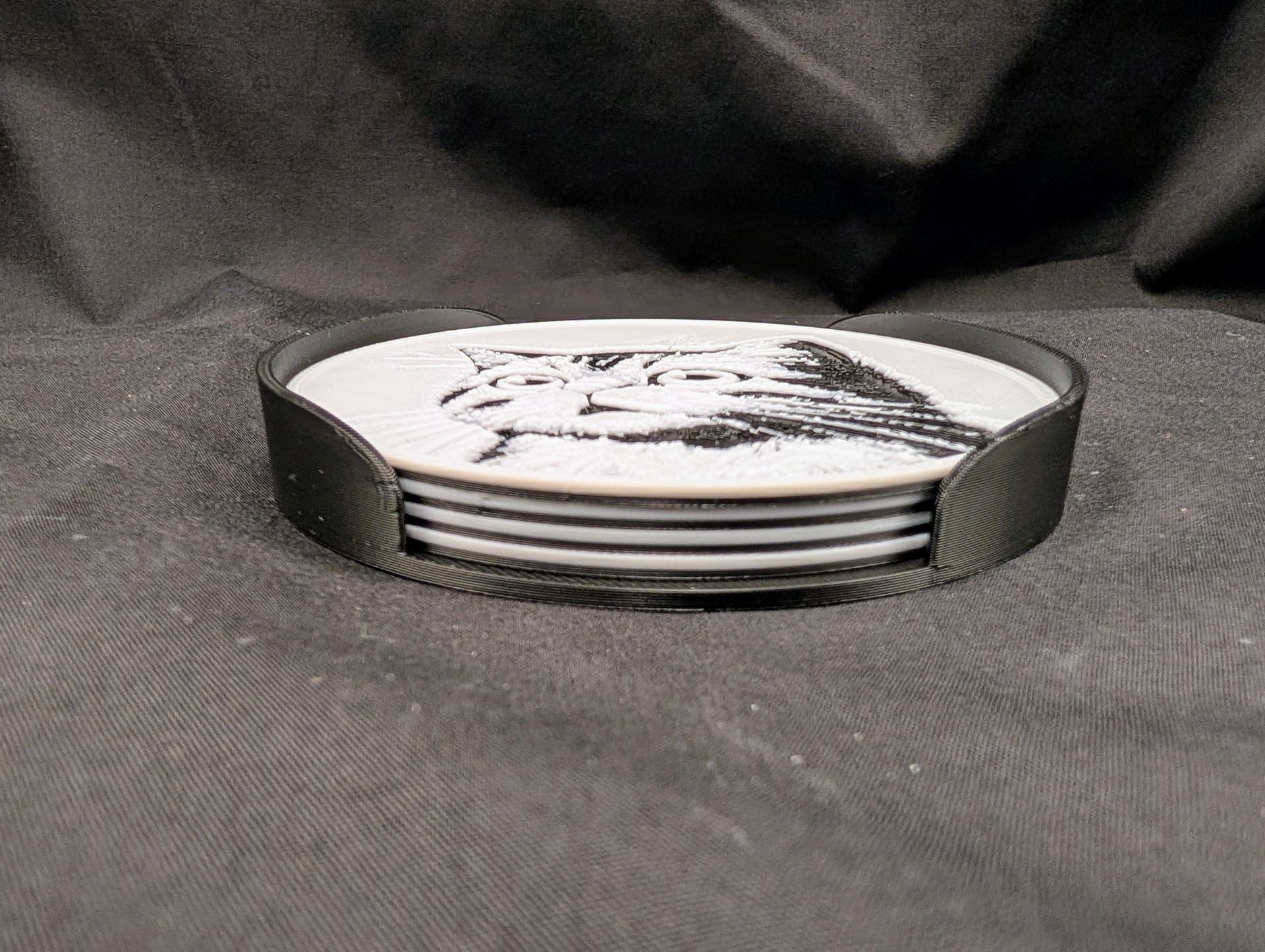 A side view of a set of four cat coasters in a holder.
