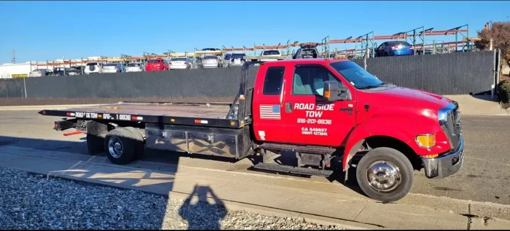 A red tow truck is parked on the side of the road.