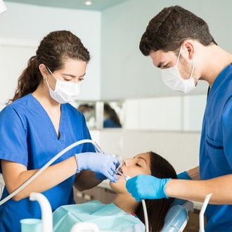 Dentist Fort Madison IA — Coworkers Treating Patient With Equipment At Clinic in Fort Madison, IA