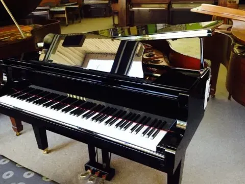 A yamaha piano is sitting in a room with other pianos