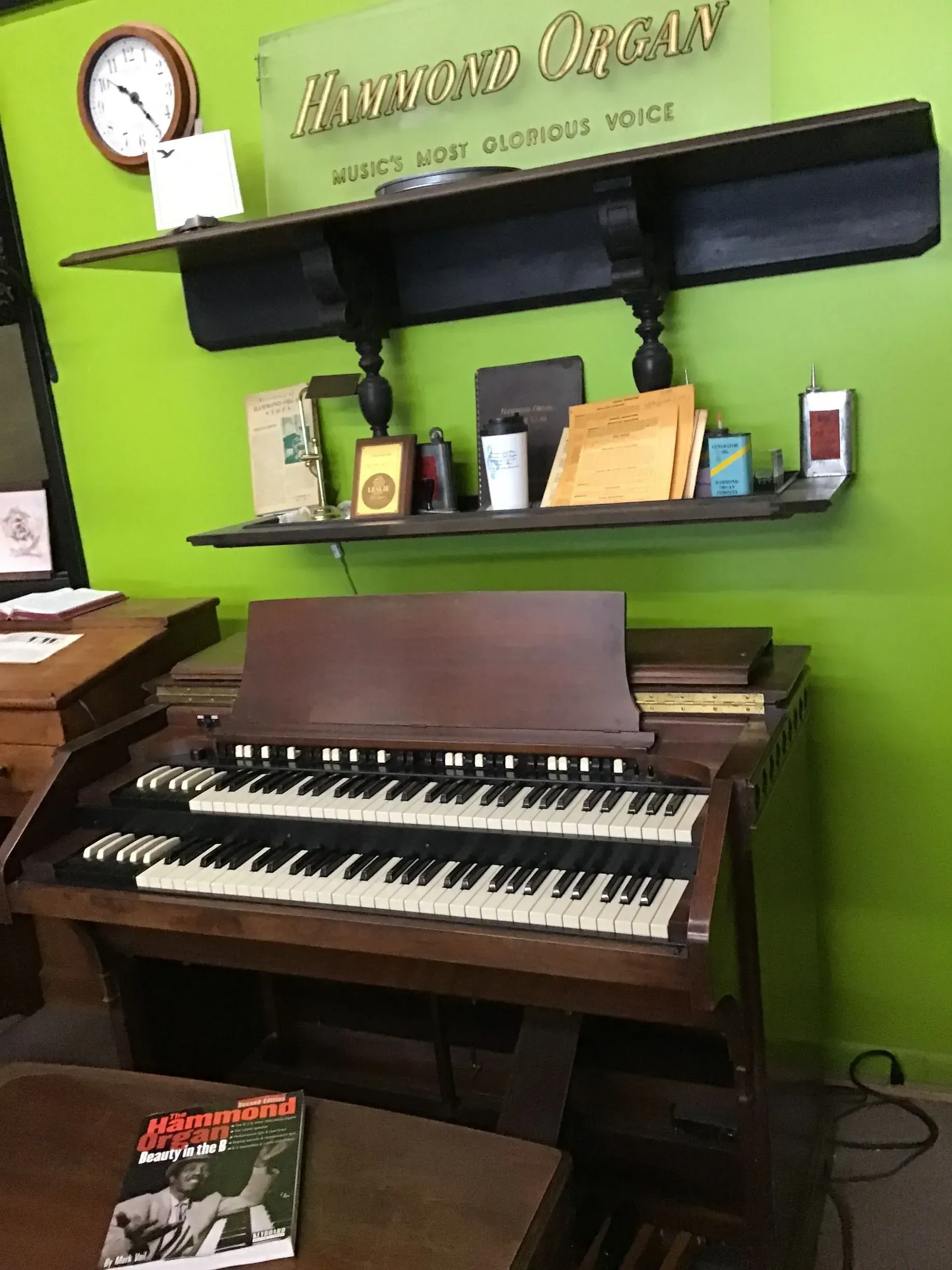 An organ is sitting on a table in front of a green wall.