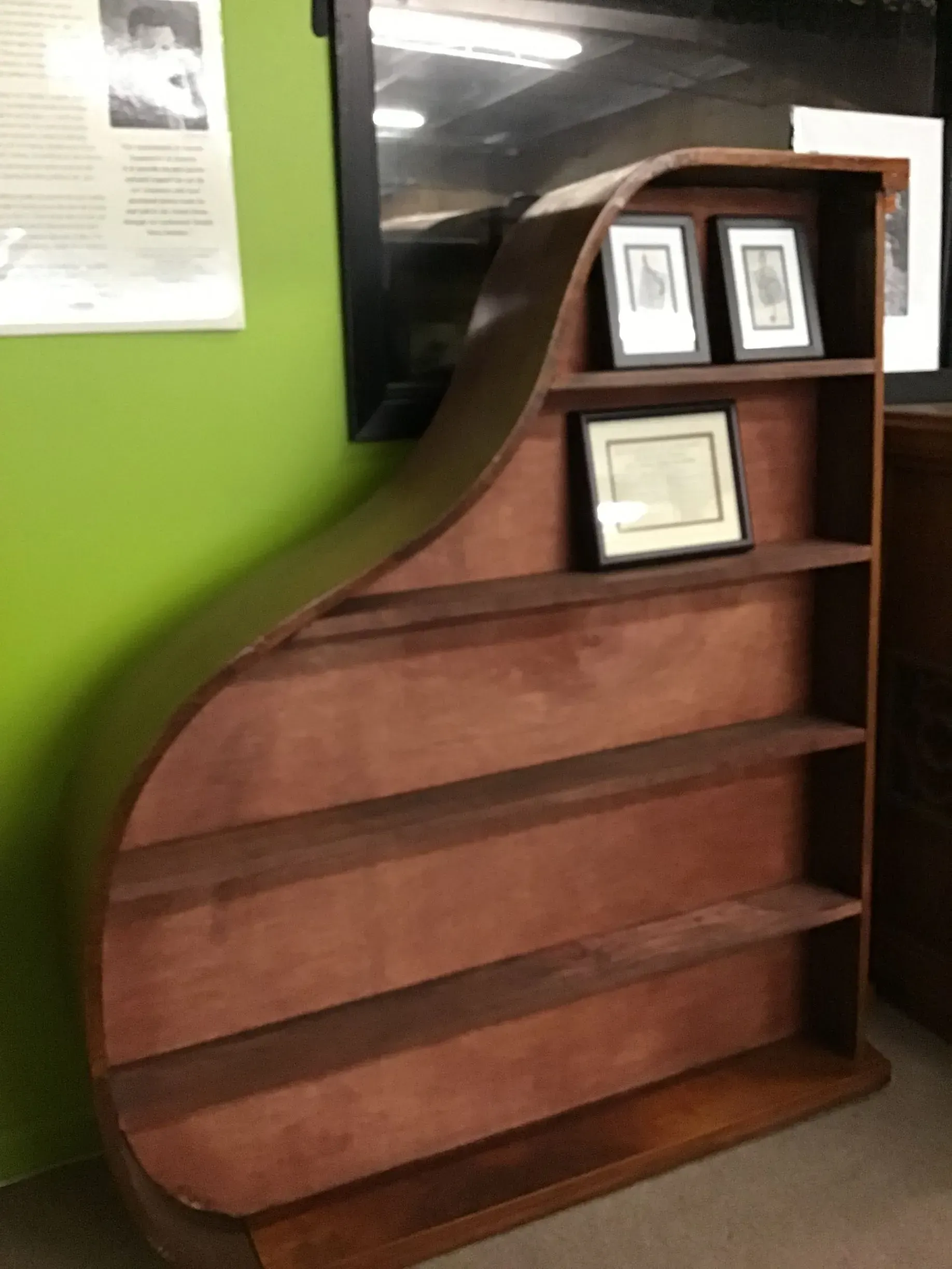 A wooden shelf with a green wall behind it