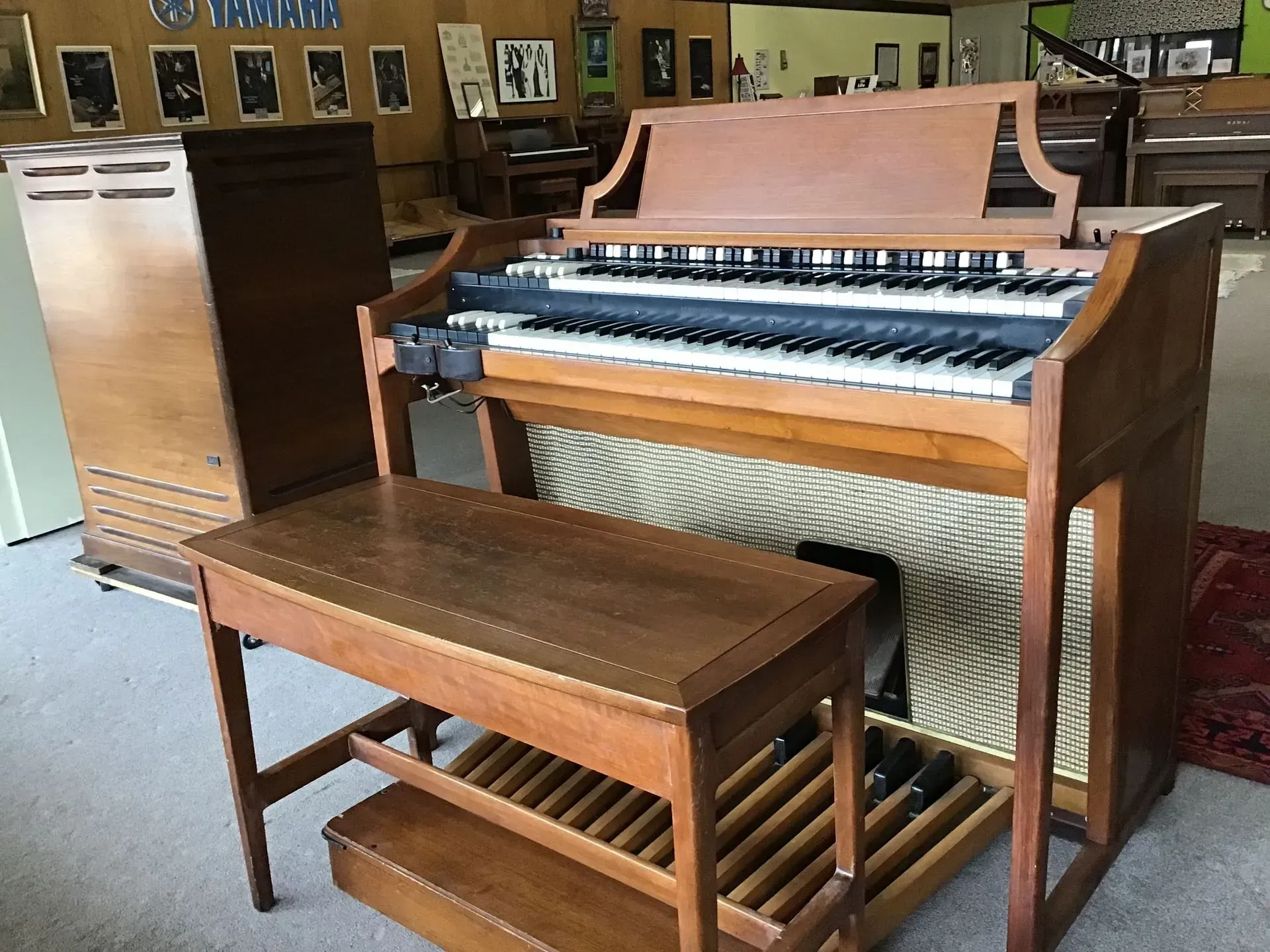 A wooden organ sits next to a wooden bench