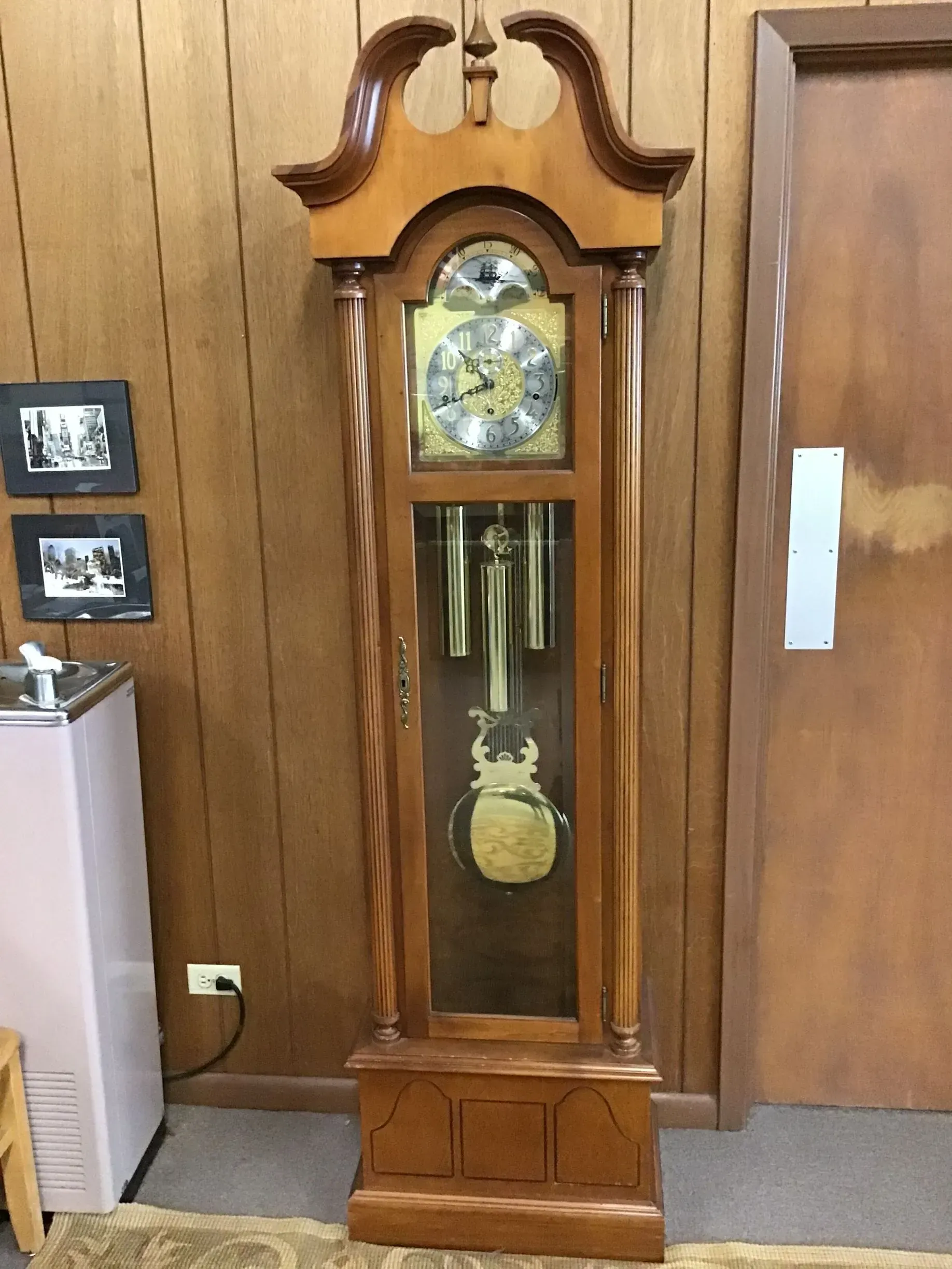 A grandfather clock is sitting in a room next to a door.