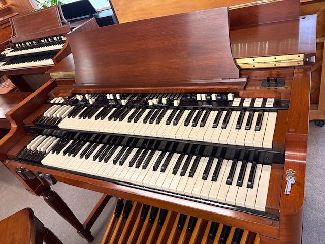 A large, wooden Hammond organ with two keyboards, pedals, and many drawbars.