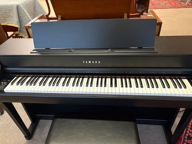 Black Yamaha digital piano with music rest and stool.