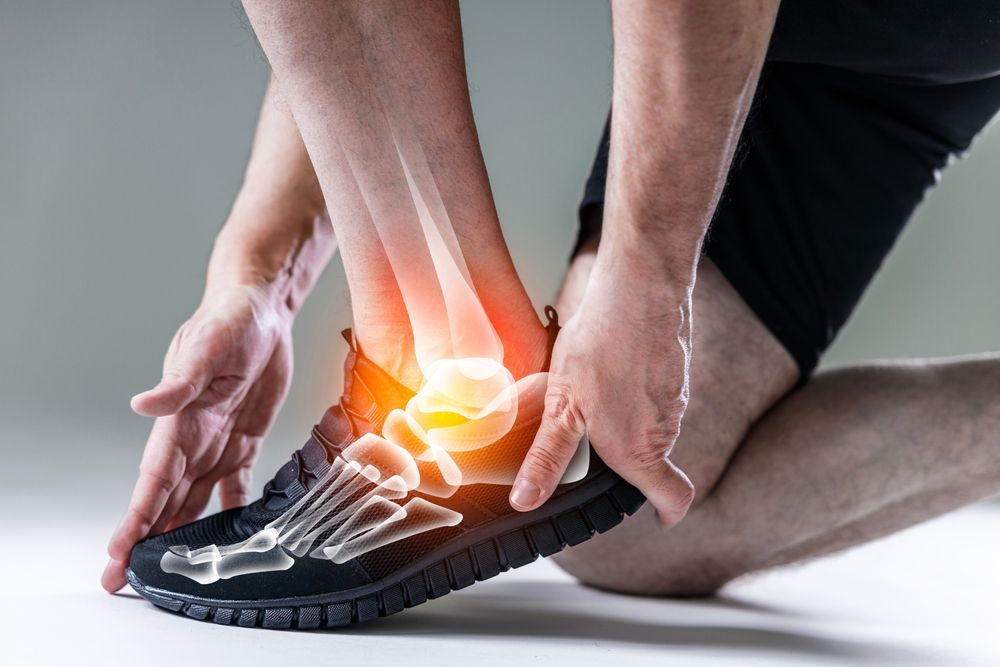 A person is holding their ankle in pain.