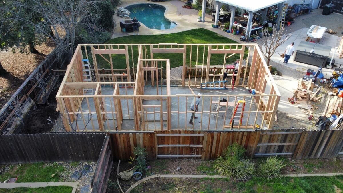 An aerial view of a house being built with a pool in the background.