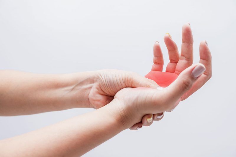 Two hands, one with a red area indicating pain in the palm.