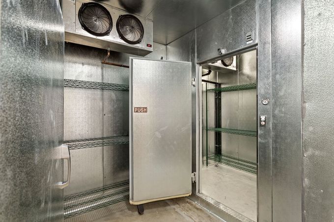 There is a refrigerator in the corner of the room with the door open.