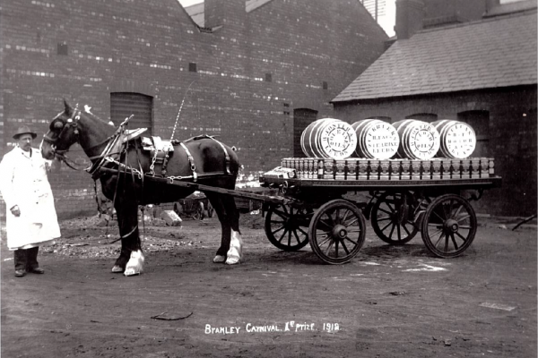 a black and white photo of a horse pulling a cart full of barrels