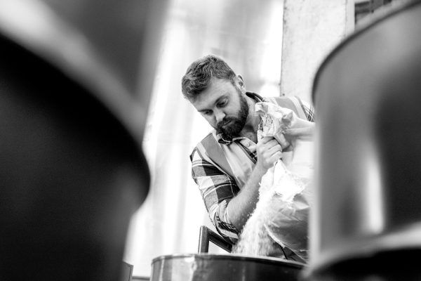 a man with a beard is standing next to a barrel in a black and white photo .