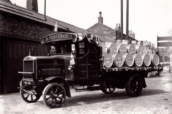 an old truck with barrels on the back is parked in front of a building .