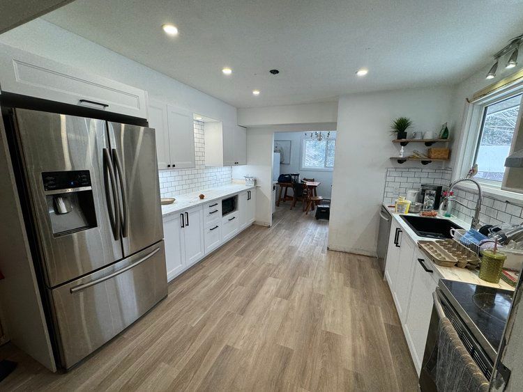 A kitchen with stainless steel appliances and white cabinets.