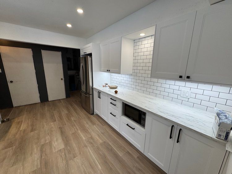 A kitchen with white cabinets and a stainless steel refrigerator.