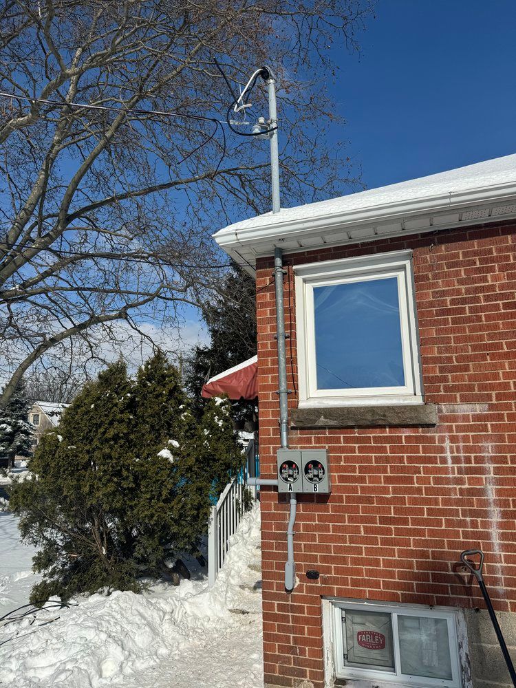 A brick house with a window and a satellite dish on top of it.